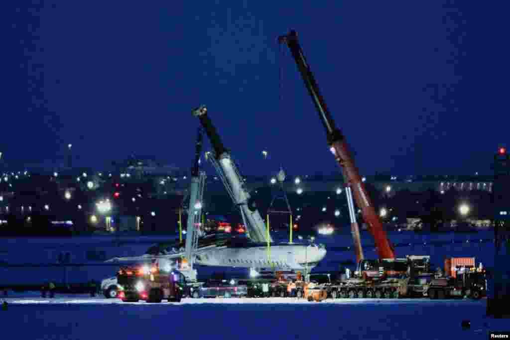 The wreckage of a Delta Air Lines operated CRJ900 aircraft is hoisted onto a truck on the runway as cleanup begins after a plane crash at Toronto Pearson International Airport in Mississauga, Ontario, Canada, Feb. 19, 2025.