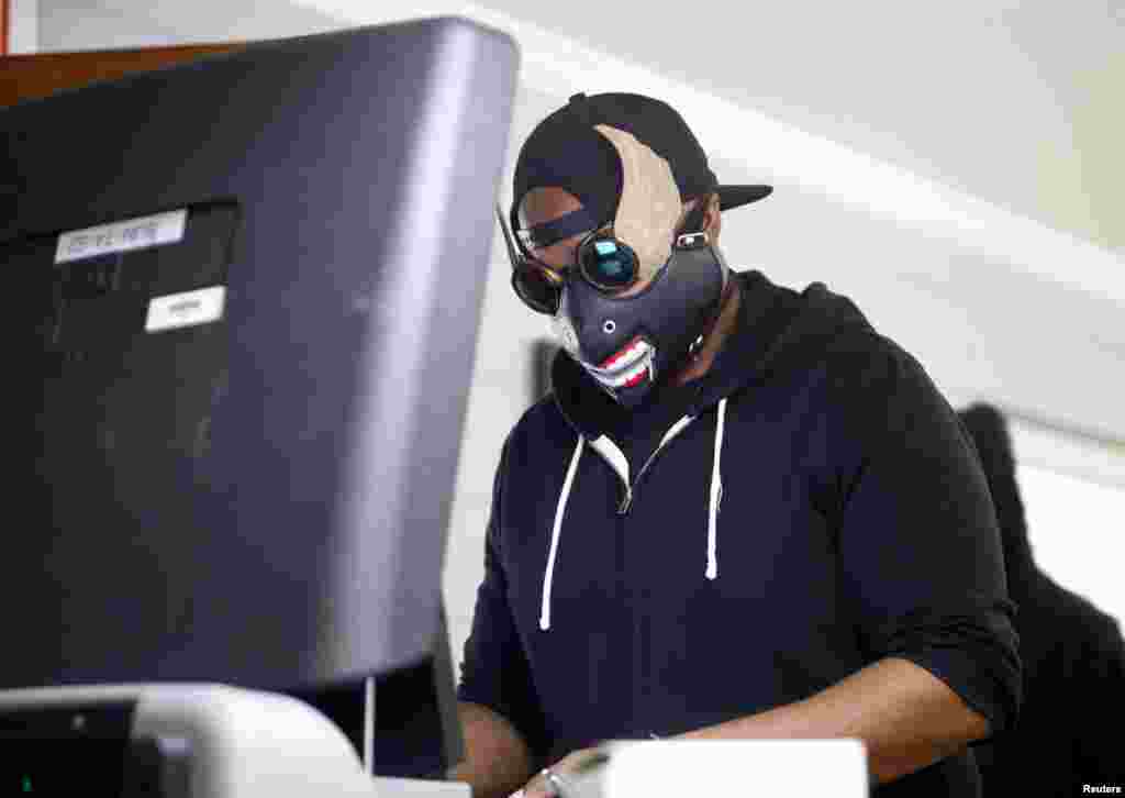 Donovan Faison wears an unusual mask and sunglasses as he feeds his ballot into a tabulator machine after voting at a polling station in Durham, Durham County, North Carolina.