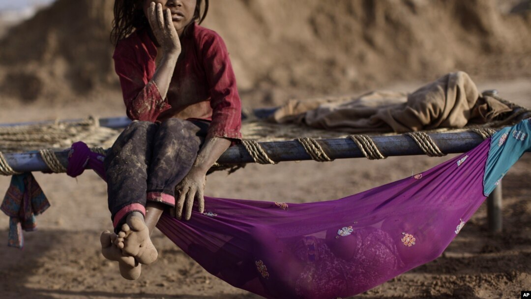 Pakistani Naginah Sadiq, 5, who works in a brick factory, rests on a bed next to her sister Shahzadi, 8 months, on World Day Against Child Labor, on the outskirts of Islamabad, Pakistan, June 12, 2012.