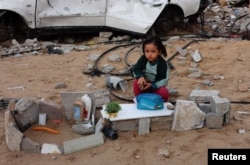 A Palestinian girl sits on the ground next to a car destroyed in a Israeli military offensive in Khan Younis in the southern Gaza Strip, Nov. 29, 2024.