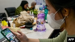 Seorang wanita menonton live streaming TikTok yang menawarkan merchandise untuk dijual di Jakarta. (Foto: AFP)