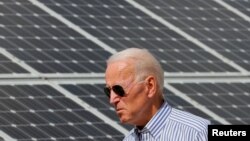 （资料照） 2020年美国民主党总统候选人拜登在普利茅斯走过一片太阳能板。