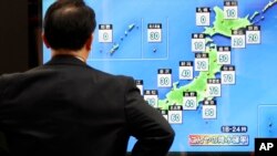 A man watches a public TV of weather forecast in Tokyo, Oct. 11, 2019. Japan's weather agency is warning a powerful typhoon may bring torrential rains to central Japan this weekend.