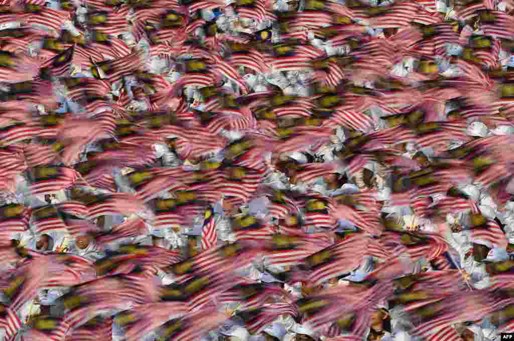 Malaysian schoolchildren wave national flags during the 60th National Day celebrations at Independence Square in Kuala Lumpur.