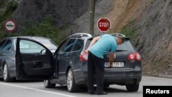 ARHIVA: Vozač uklanja nalepnicu sa registarskih tablica na prelazu Jarinje (Foto: REUTERS/Ognen Teofilovski)