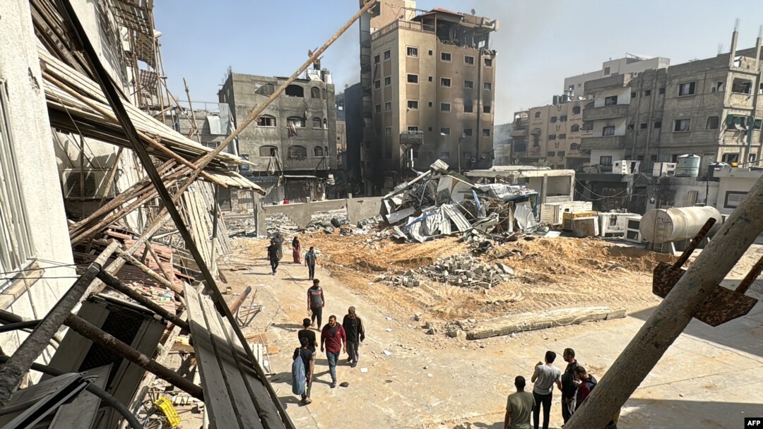 Palestinians walk past damaged and destroyed buildings in Beit Lahia the northern Gaza Strip, Oct. 26, 2024. 