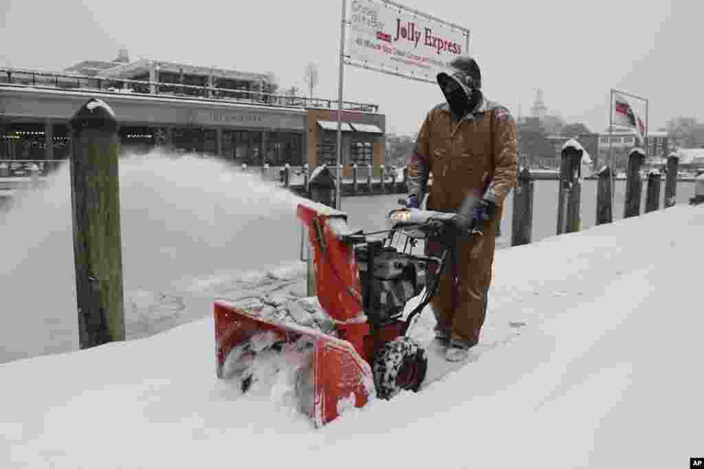 Tony Savage, que trabalha para a cidade de Annapolis, limpa a neve ao longo do City Dock em Annapolis, Maryland, a 6 de janeiro de 2025.