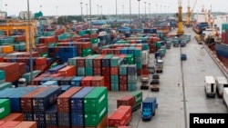 Workers are seen among the containers at Asia World port in Yangon, Myanmar, July 2, 2014. 