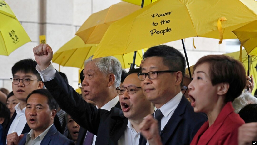 "Occupy Central" leaders, from right, Tanya Chan, Chan Kin Man, Benny Tai, Chu Yiu Ming and Lee Wing Tat shout slogans before entering a court in Hong Kong, Nov. 19, 2018.