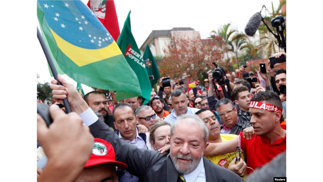 Former Brazilian President Luiz Inacio Lula da Silva carries a Brazilian flag as he arrives at Federal Justice, for a testimony in Curitiba, Brazil, May 10, 2017.