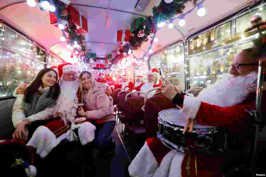 Musician dressed as Santa Claus takes a photo with passengers in a bus decorated for Christmas and New Year celebrations in central Saint-Petersburg, Russia, Dec. 24, 2019.