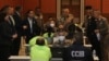 In this photo released by Thailand's Cyber Crime Investigation Bureau, policemen talk to suspects, wearing light green shirts, at the Cyber Crime Investigation Bureau in Bangkok, Thailand, March 22, 2023. 