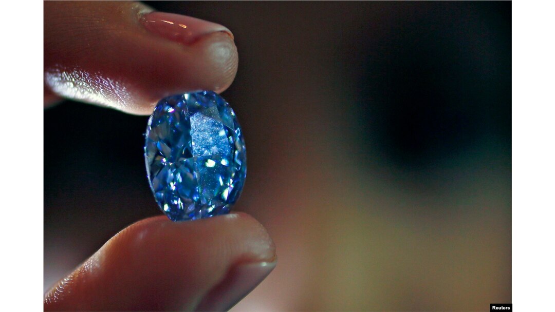 An employee holds a 10.10-carat internally flawless blue diamond at Sotheby's auction house in London, March 15, 2016.