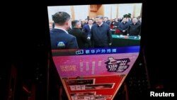 A giant screen at a shopping mall in Beijing shows news footage of Chinese leader Xi Jinping shaking hands with Alibaba founder Jack Ma at a private enterprise forum, Feb. 17, 2025. 