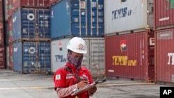 Seorang pekerja sedang mencatat data dekat tumpukan peti kemas di pelabuhan Tanjung Priok, Jakarta, 8 Oktober 2021. (Foto: Tatan Syuflana/AP Photo)