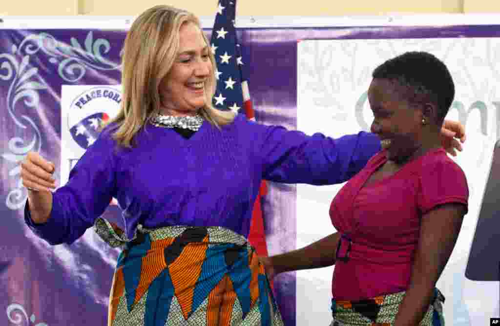 Một thiếu nữ giúp Ngoại trưởng Clinton mặc chiếc váy, theo trang phục cổ truyền của địa phương, khi bà nói chuyện tại Trại GLOW, do Đoàn Hòa Bình điều hành ở Lilongwe, Malawi, 5-8-2012.