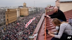 Pristalice beloruske opozicije sa krovova gledaju marš hiljada građana ka Trgu nezavisnosti u Minsku, 23. avgusta 2020. 