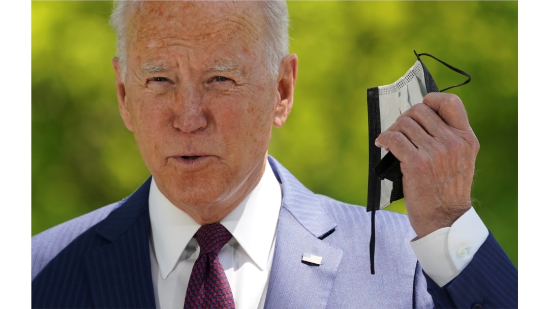 U.S. President Joe Biden pulls off his face mask as he arrives to speak about loosening coronavirus mask guidelines, outside the White House in Washington, April 27, 2021.