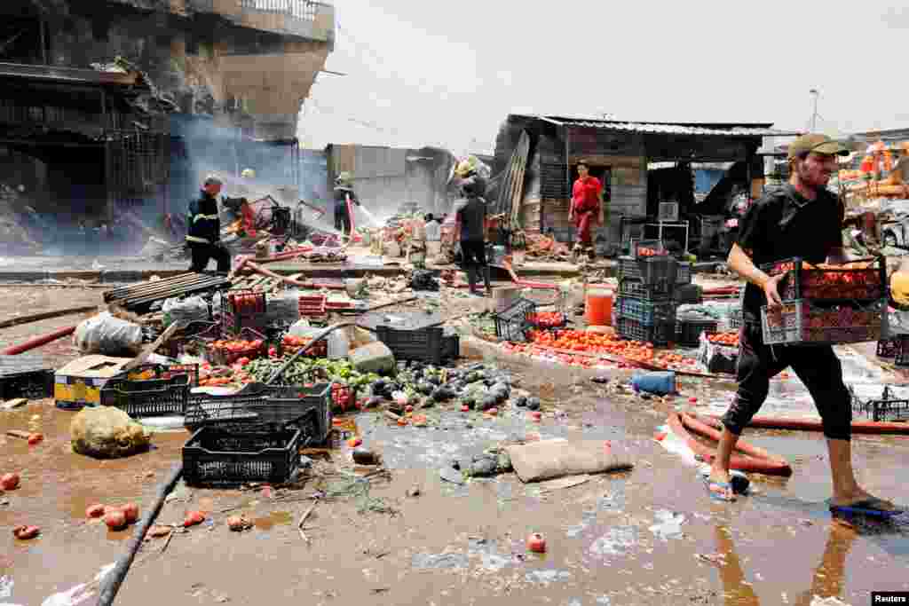 People gather at the site of a car bomb attack in Jamila market in Sadr City district of Baghdad, Iraq.