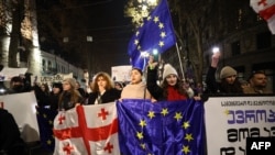 Демонстранты держат грузинские и европейские флаги во время акции протеста против переноса правительством переговоров о вступлении в Европейский союз. Тбилиси, 11 декабря 2024 года.