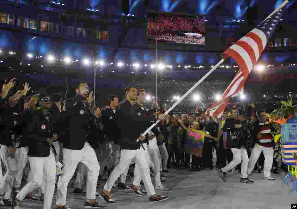 Michael Phelps oo dhinaca dabbaasha ku guuleystay billado badan ayaa sida calanka Maraykanka isagoo hoggaaminaya kooxda Maryakanka uga qeybgalaysa tartanka olombikada ee Rio de Janeiro, Brazil, Aug. 5, 2016.