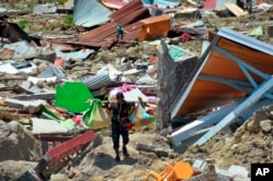 Čovek nosi stvari koje je izvukao iz ruševina, nakon što su snažan zemljotres i cunami pogodili Palu, Celtrana Suavesi, Indonezija, 1. oktobra 2018.