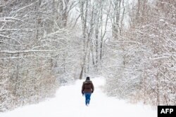A woman walks through a snow covered path in Centreville, Maryland, on February 12, 2025, after a winter storm brought heavy snow across the state and region. (Photo by Jim WATSON / AFP)