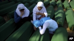 Porodice pored kovčega sa posmrtnim ostacima žrtava maskra u Srebrenici
