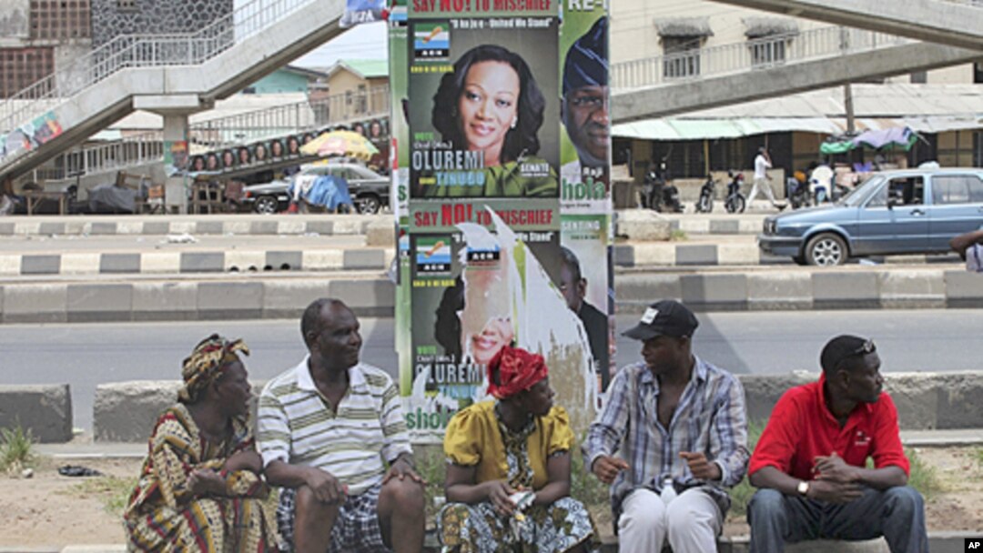 Wasu 'yan Nigeriake nan zaune a karkashin gada dauke da takardun gangamin zabe na Fasta a Ojuelegba jihar Ikkon Nigeria.