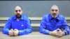 A web page on the website of the Russian news agency RIA Novosty identifies the man sitting at the right as Maxim Shugaley, and the man on the left as Samer Sueifan. There is no description of where and when the photo was taken.