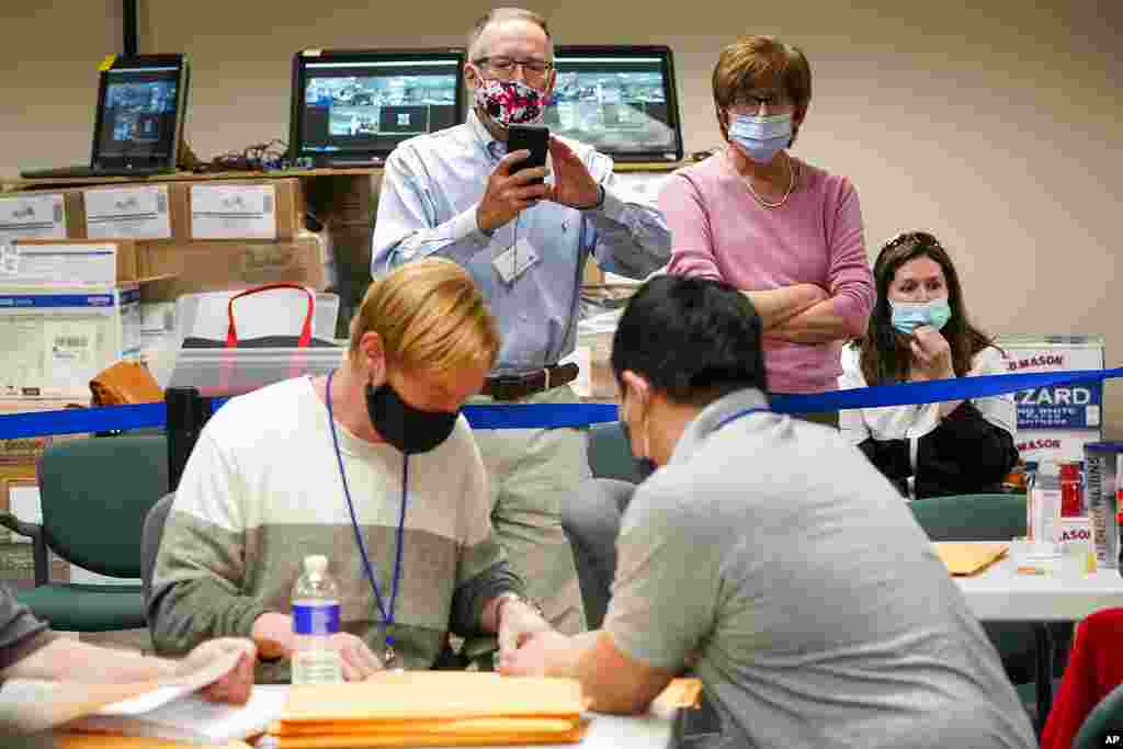 Republican canvas observer Ed White, center, and Democratic canvas observer Janne Kelhart watch as Lehigh County workers count ballots as vote counting in the general election continues, in Allentown, Pennsylvania.