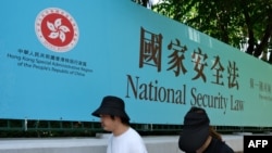 資料圖片：行人走過香港街頭港版國安法的宣傳牌。 （2020年7月15日）