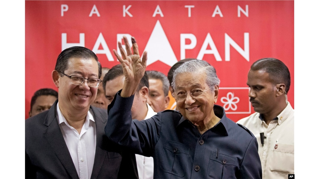 Malaysia's Prime Minister Mahathir Mohamad, center, waves next to newly appointed Finance Minister Lim Guan Eng, left, after a press conference to announce his cabinet members in Petaling Jaya, May 12, 2018.