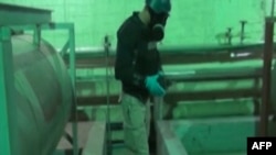 Syria -- A TV grab shows an inspector from the Organisation for the Prohibition of Chemical Weapons (OPCW) at work at an undisclosed location in Syria, October 8, 2013