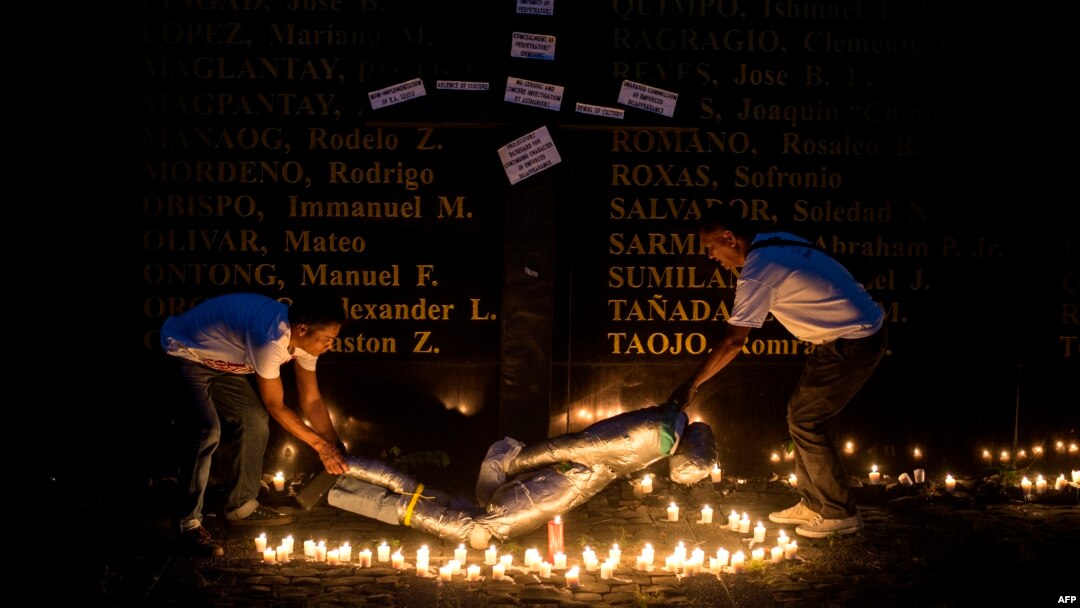 FILE - People lift a mock victim during a prayer vigil in support of the families of victims of extra-judicial killings in Manila on April 12, 2017.