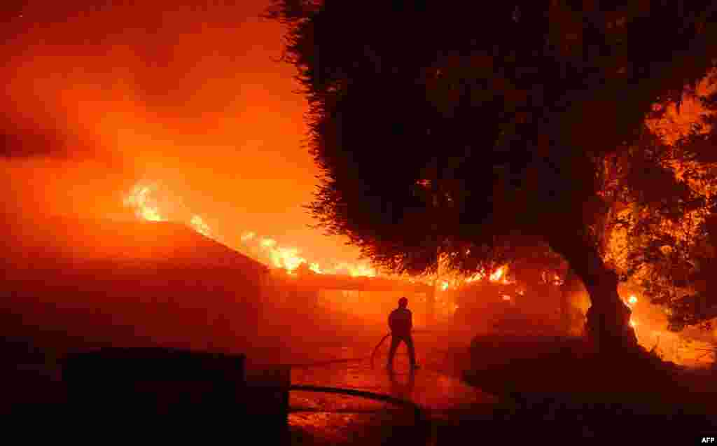 Um bombeiro trabalha no local, enquanto dezenas de casas continuam em chamas durante o incêndio em Eaton, na zona de Altadena, no condado de Los Angeles, na Califórnia, a 8 de janeiro de 2025.
