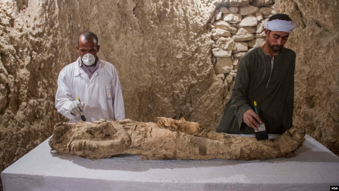 Egyptian excavation workers restore a mummy in a newly discovered tomb in the Draa Abul Naga necropolis on Luxor’s West Bank known as KAMPP 150, in Luxor, Egypt, Dec. 9, 2017.(H. Elrasam/VOA)