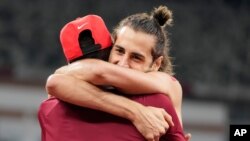 Gianmarco Tamberi, of Italy, embraces fellow gold medalist Mutaz Barshim, of Qatar, after the final of the men's high jump, Aug. 1, 2021, at the 2020 Summer Olympics in Tokyo.