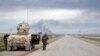 FILE - Smoke billows in the background as Kurdish peshmerga fighters take positions on the side of a road in the northern Iraqi city of Kirkuk, Jan. 30, 2015.