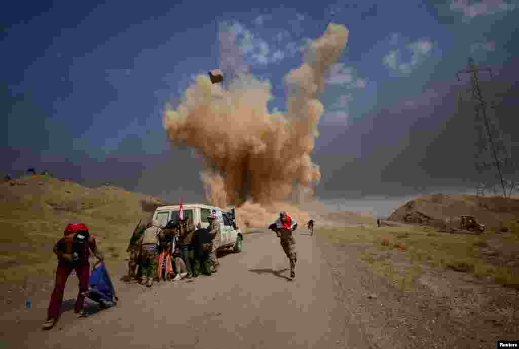 Shi'ite Popular Mobilization Forces (PMF) run and cover themselves from a bomb attack in outside of Hawija, Iraq, Sept. 30, 2017.