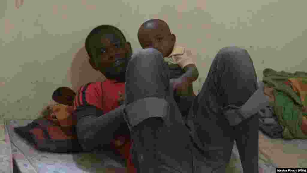Un ex-combattant de Boko Haram joue avec un enfant dans le centre de transition des repentis de Diffa, Niger, le 17 avril 2017 (VOA/Nicolas Pinault)