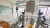 A medical staff is reflected in a mirror as she attends to a COVID-19 patient at a special ward at Arwyp Medical Centre, as South Africa is about the reach a milestone of 1 million infections, in Kempton Park, Dec. 25, 2020.