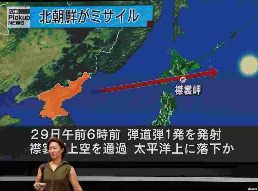 A woman walks past a large TV screen showing news about North Korea's missile launch in Tokyo, Japan.
