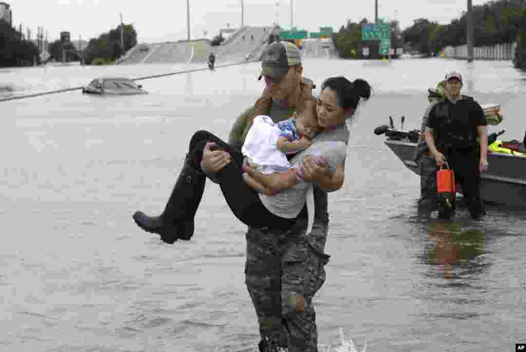 Houston Police SWAT officer Daryl Hudeck carries Catherine Pham and her 13-month-old son Aiden after rescuing them from their home surrounded by floodwaters from Tropical Storm Harvey, in Houston, Texas, Aug. 27, 2017.