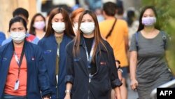 Office employees wearing facemasks walk along a street in Manila on January 30, 2020.