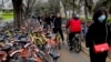 Residents ride bicycles from bike-sharing company Ofo try to pedal through a sidewalk crowded with bicycles from the bike-sharing companies Ofo, Mobike and Bluegogo, near a bus stand in Beijing, China, March 23, 2017. As many as 2.2 million of these two-wheelers have been deployed, which are available for rent for as little as U.S. 7 cents for half an hour, in the latest symbol of heavy spending in China's internet sector where startups are in a race to attract more users to their services.