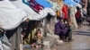 Perempuan dan anak-anak Palestina duduk di luar tenda yang menampung pengungsi Palestina di Rafah di Jalur Gaza selatan, di tengah konflik Israel-Hamas yang terus berlanjut.