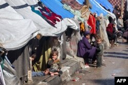 Žena i deca sede ispred šatora, u skloništu za raseljene Palestince u Rafi, na jugu Pojasa Gaze, 8. februara 2024.