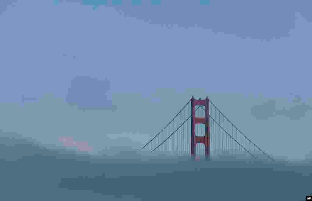 A tower of the Golden Gate Bridge is shown over fog in San Francisco.