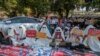FILE - Hooded demonstrators display placards accusing China of supporting Myanmar's military during a protest against the recent coup, outside the Chinese Embassy in Yangon, Myanmar, Feb. 11, 2021.